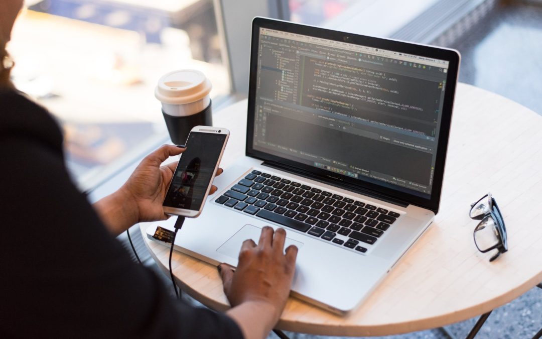 person holding smartphone while using laptop